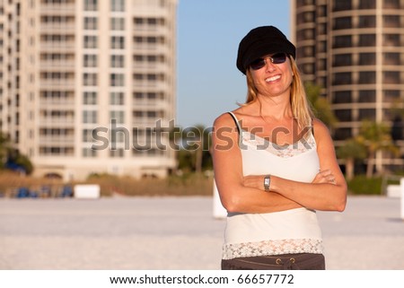 Pretty and sexy middle aged woman posing on the beach in the late afternoon wearing a hat and sunglasses.