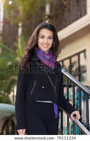 Pretty multicultural young woman on the steps of an outdoor shopping mall.