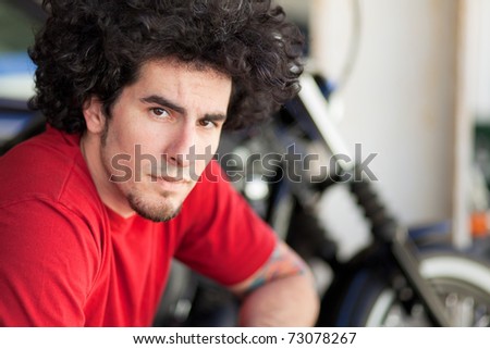 Handsome young man with long curly hair and a goatee in an urban downtown setting.