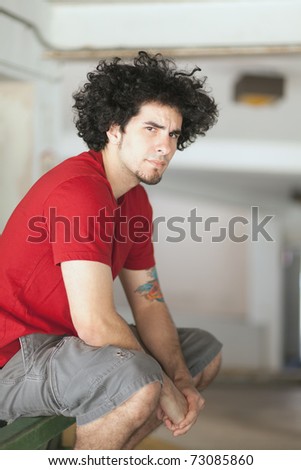 Handsome young man with long curly hair and a goatee in an urban downtown setting.