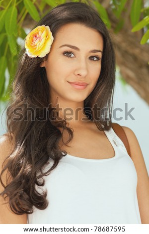 Beautiful young woman in a outdoor garden patio setting with a flower in her hair.