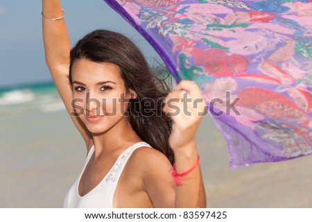 Beautiful young woman holding a purple shawl against the ocean breeze enjoying the South Beach shoreline in Miami.