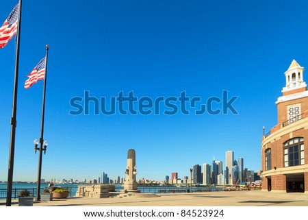 Navy Pier in Chicago with downtown skyline and American flags on a clear blue sky day.