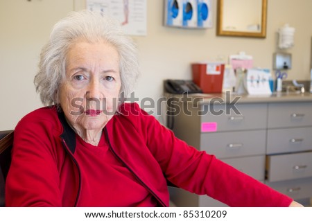 Elderly 80 year old woman with Alzheimer waiting for her doctor in the examination room.