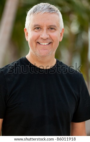Handsome unshaven middle age man in an outdoor setting.