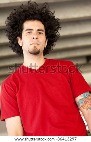 Handsome young man with long curly hair in a parking garage.