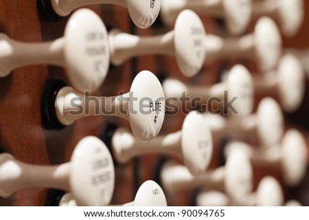 Close up view of the stop knobs of a church pipe organ with a shallow depth of field and selective focus.