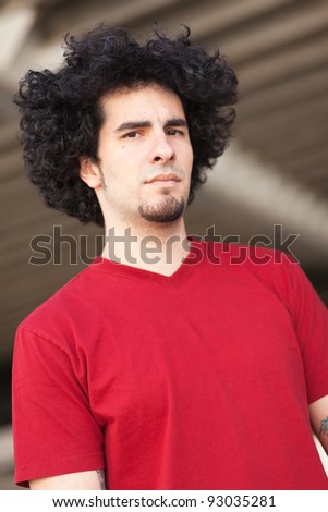 Handsome young man with long curly hair and goatee outdoors.