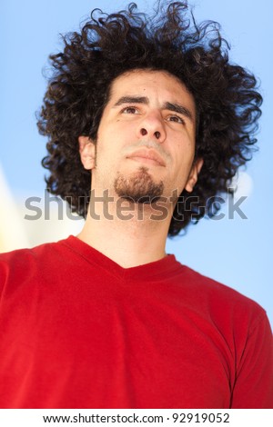 Handsome young man with long curly hair and goatee outdoors.