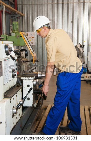 the mechanic works at the lathe at factory
