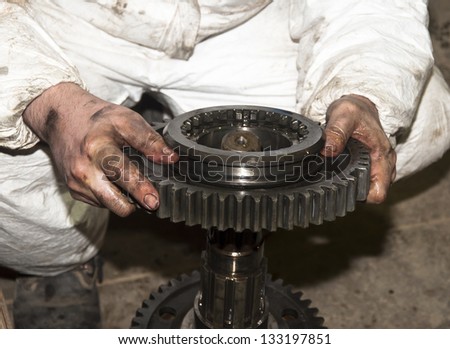 the worker dirty hands holds a big gear in auto service