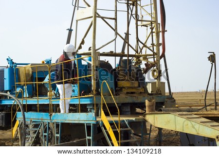 the worker costs on the drilling rig, is photographed at a short distance