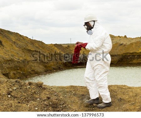 worker wears protective clothing and mask costs about poisoned lake on the industrial site