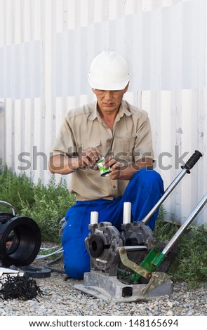 the mechanic works at a welding machine for connection of plastic pipes