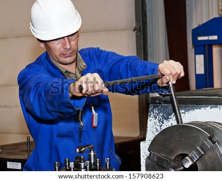 The industrial area, the mechanic adjusts the machine, in hands the tool.