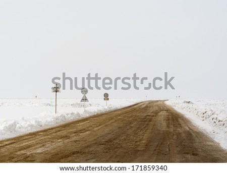 Crossroad in a stormy winter day with road signs