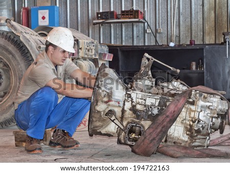 worker in protective clothes repairs the automobile mechanism
