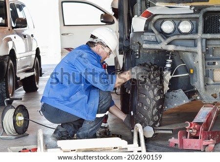 Industrial area. Mechanic in protective clothes repairs the automobile mechanism.