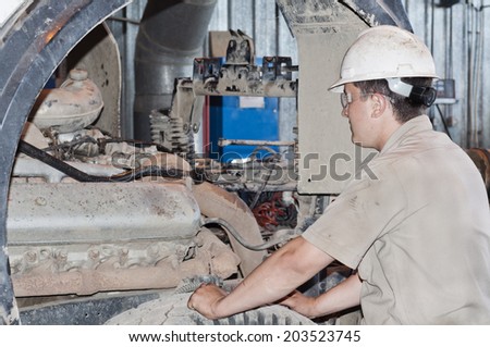 The mechanic looks at the truck engine before repair