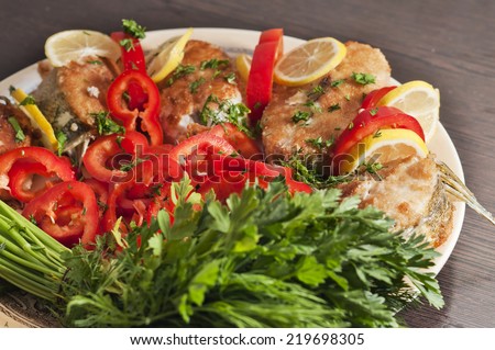 A plate of salad with fish in side view.
