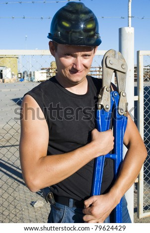 worker holding a bolt cutter and looks into the camera