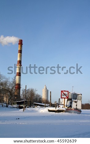 old Ship on frozen river with traffic sign, chimney and modern building