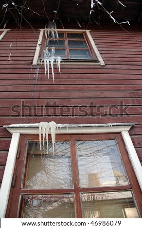 Icicles hanging from roof on idyllic wood house