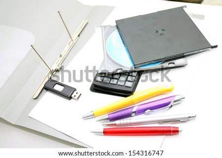 Office accessories - pens, the calculator and compact disks on a white background