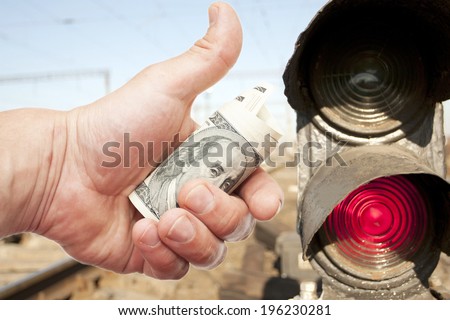 Man\'s Hand with notes of US dollars against light-odds of the railroad