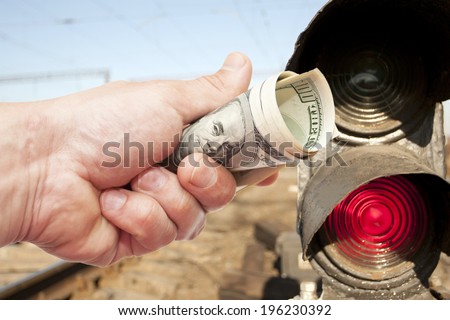 Man\'s Hand with notes of US dollars against light-odds of the railroad