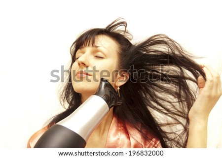 The woman dries hair the hair dryer on a white background