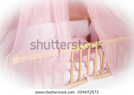 Children's wooden bed with pink bed linen on a white background