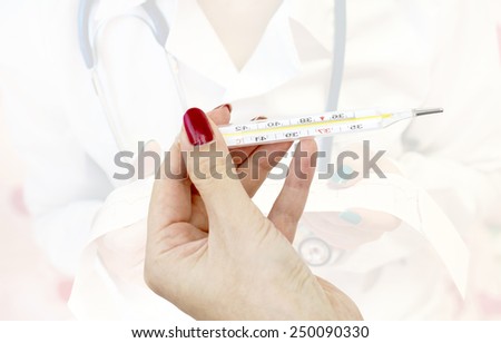 A Mercury thermometer for measuring the temperature in the hands against the background of a doctor in a white lab coat