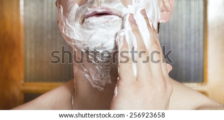 The process of applying shaving foam on the face in the bathroom