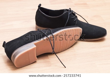 Black suede shoes with laces on a background of wooden parquet