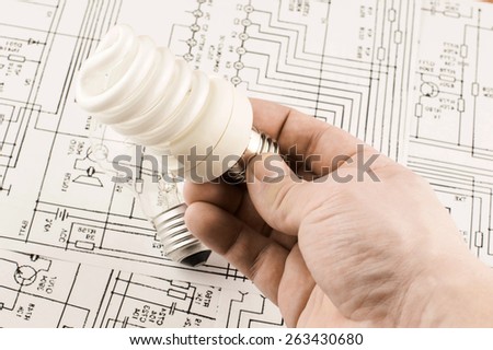 Fluorescent lamp in hand on background drawings circuits