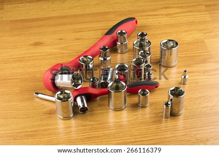 Ratchet and a set of different attachments to tighten the bolts on the background of the wooden floor