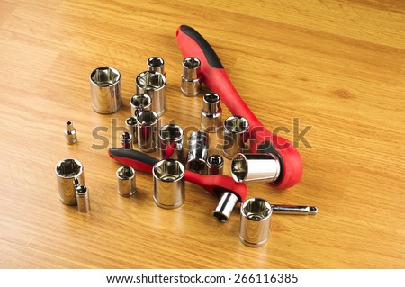 Ratchet and a set of different attachments to tighten the bolts on the background of the wooden floor