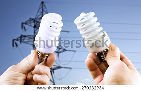 Fluorescent light bulbs in hands on background of electric line support