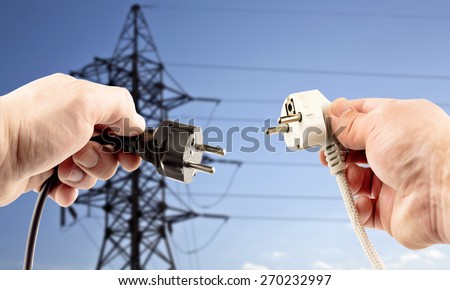 Plugs in hand on blue background power lines