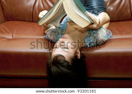 The woman with the book lying on a leather sofa