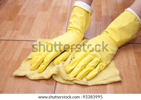 Cleaning of a kitchen tile by yellow rubber gloves with a rag