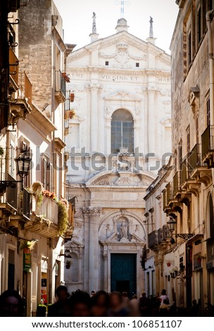 A view of the main street in Lecce with the crowds promenading in the late afternoon sun. The church of St Irene, built from 1591 by Francesco Grimaldi, provides the backdrop.
