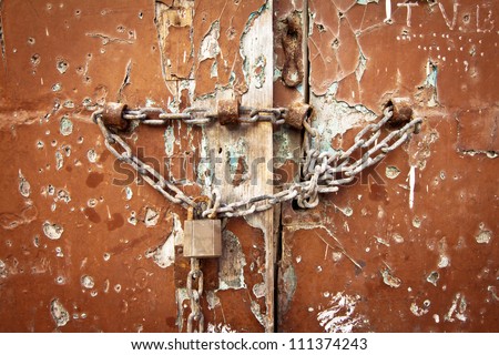 Weathered old door with lock and chain, landscape orientation.