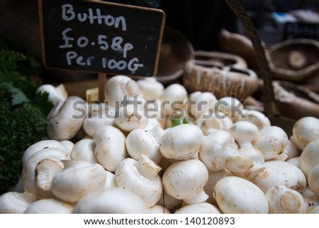 Heaps of button mushrooms for sale at farmers market. Shallow depth of field.