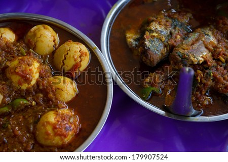 Myanmar street food: boiled eggs in red sauce with peppers and other vegetables, and meat with vegetables in sauce.
