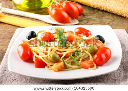 Spaghetti with fresh tomatoes, olives and mint on complex background
