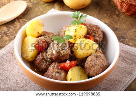 Meatballs with tomato sauce with potatoes in broth on complex background