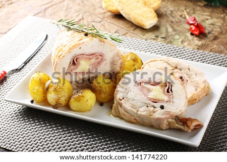 Roulade of stuffed chicken with potatoes and rosemary on complex background