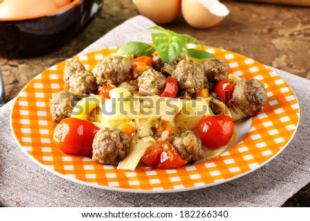 Fresh egg pasta with cherry tomatoes and meatballs on complex background